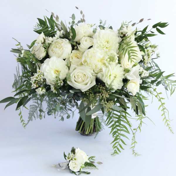 Large white rose and peony bouquet with trailing greenery and a matching white boutonniere.