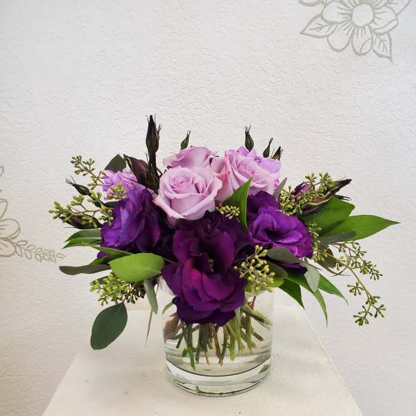 Purple and pink rose bouquet in a clear glass vase