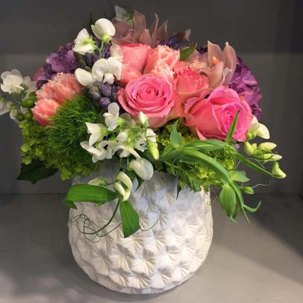 Pink and purple floral arrangement in a white textured vase