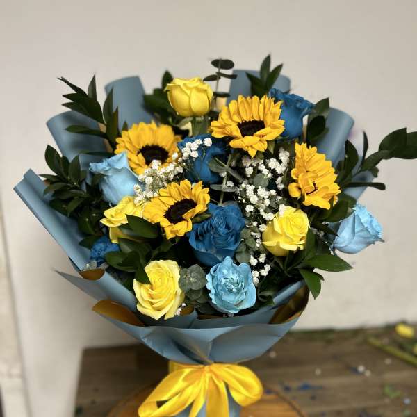 Bouquet of yellow sunflowers and blue and yellow roses wrapped in blue paper