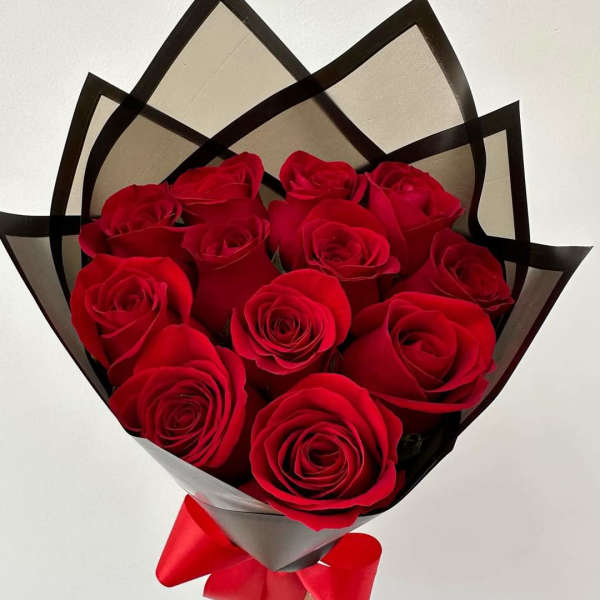 Bouquet of red roses wrapped in black and gray paper with a red ribbon