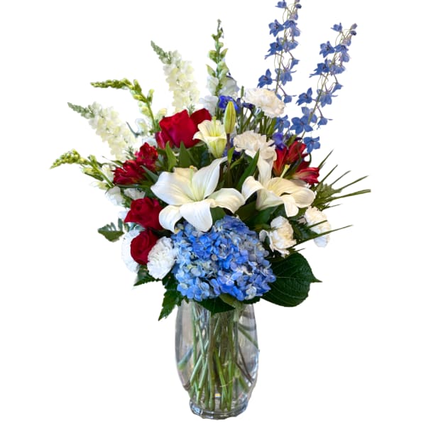 Mixed bouquet of red, white, and blue flowers in a clear glass vase