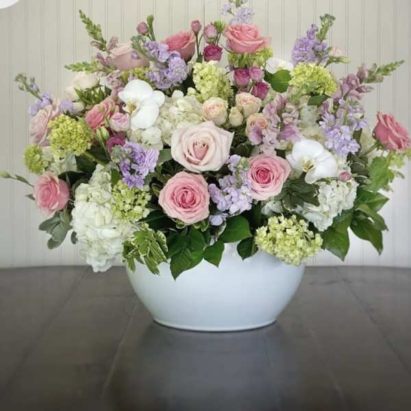 Large pastel flower arrangement in a white bowl vase