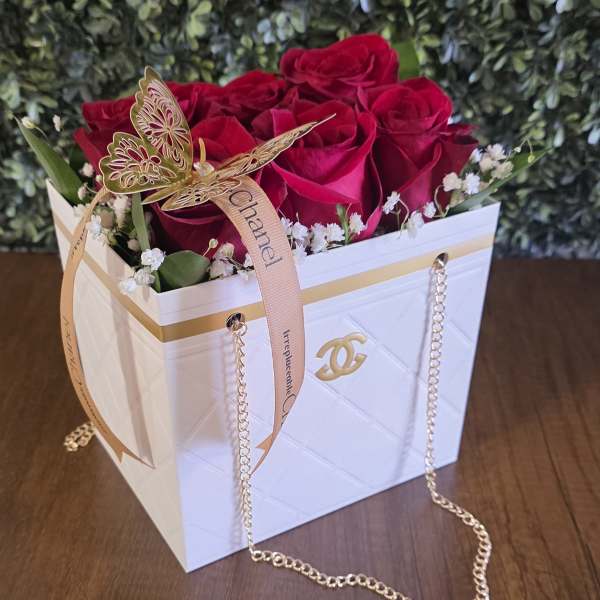 Red roses in a white gift box with a gold butterfly ribbon