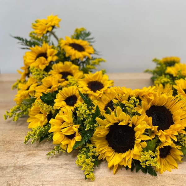 Sunflower arrangement with yellow filler flowers on a wooden table