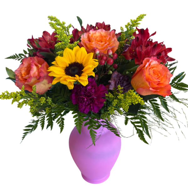 Mixed bouquet with sunflowers, roses, and red blooms in a purple vase