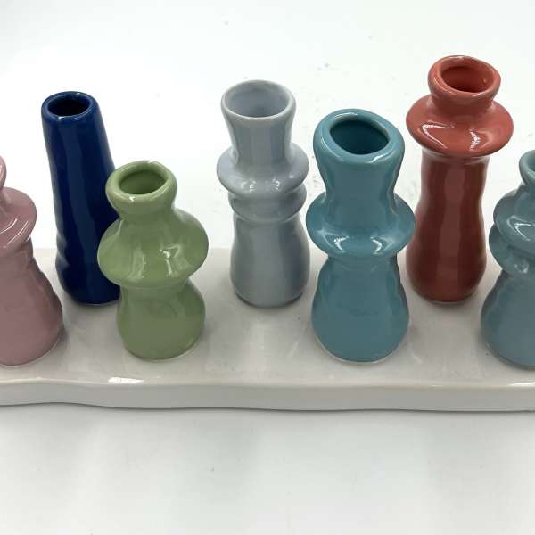 Colorful ceramic bud vases arranged on a white tray