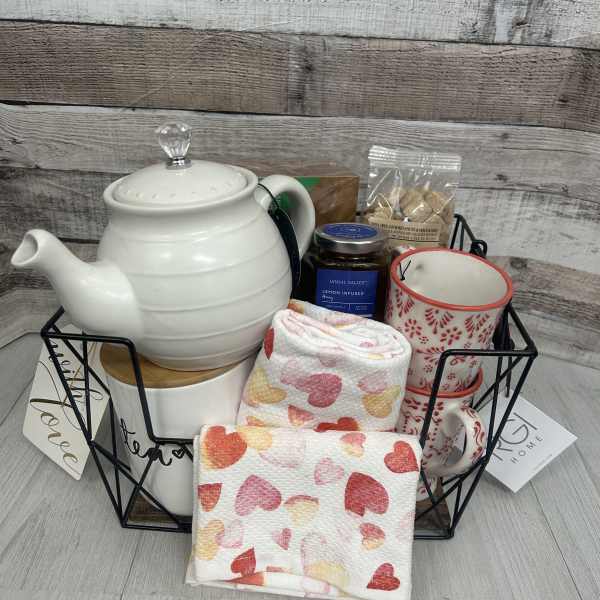 Gift basket with a teapot, mug, honey, and heart-patterned towels