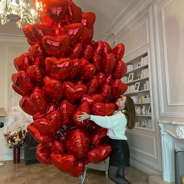 Large cluster of red heart-shaped balloons in a room
