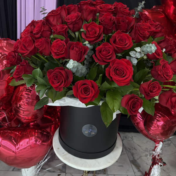 Large bouquet of red roses in a black hat box with red heart balloons