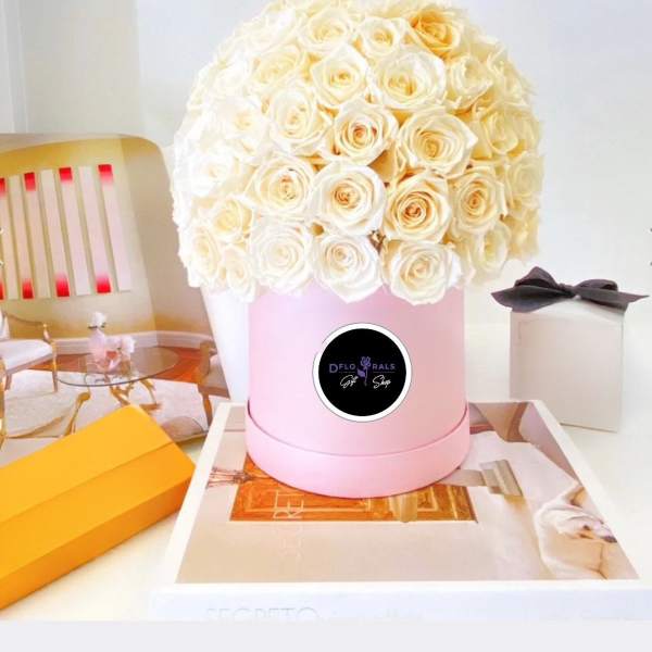 Cream rose bouquet in a pink round box with gift boxes nearby