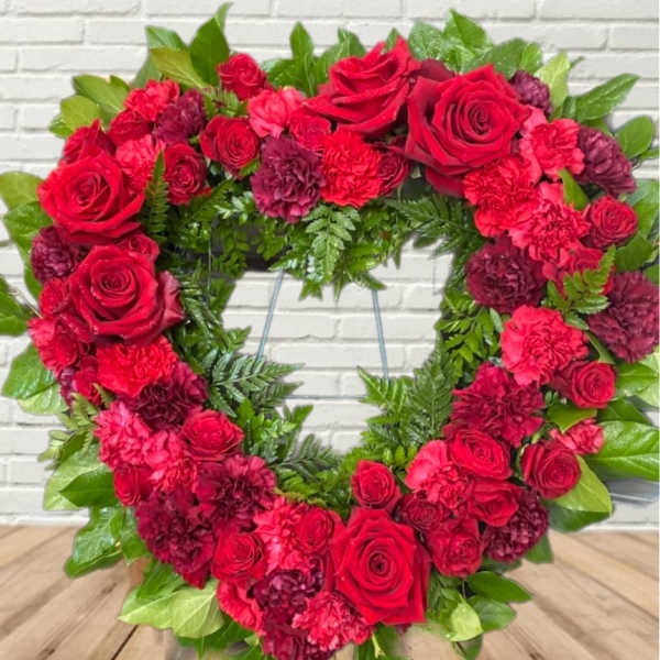 Heart-shaped wreath of red roses and carnations with green foliage
