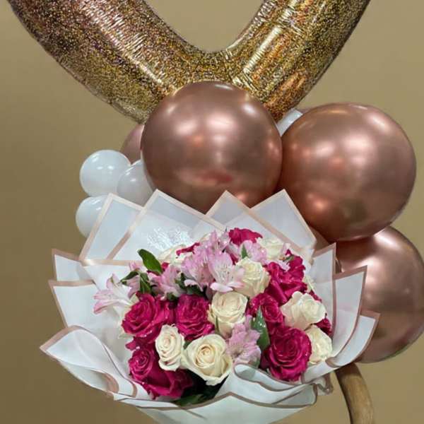 Heart-shaped balloons above a bouquet of pink and white roses