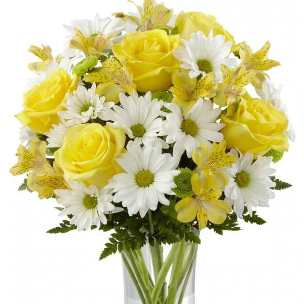 Yellow roses and white daisies in a clear glass vase