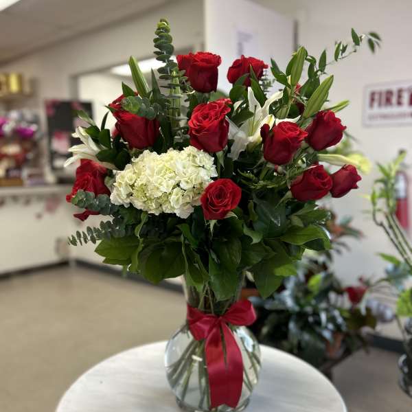 Red roses and white hydrangea in a glass vase with a red ribbon