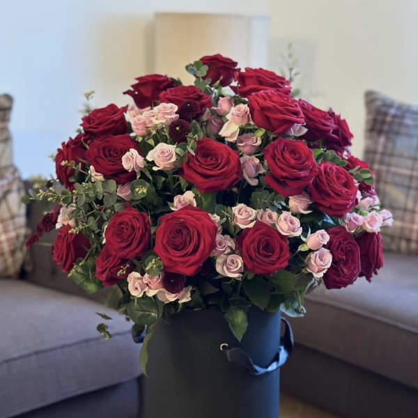Bouquet of red and blush roses in a tall black hatbox