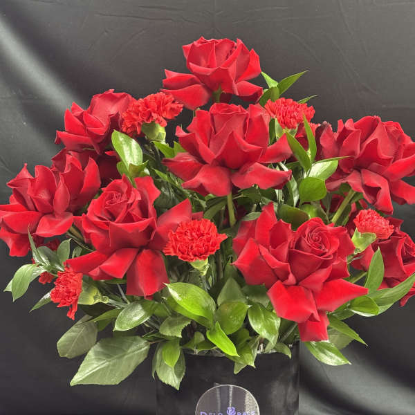 Red roses and carnations in a black hat box
