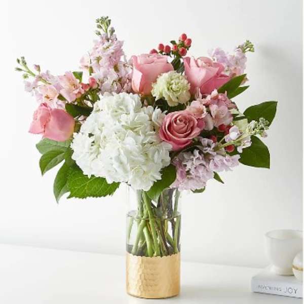 Pink and white bouquet in a clear glass vase with a gold base