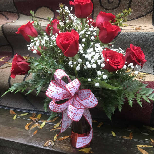 Bouquet of red roses with baby's breath in a vase and ribbon