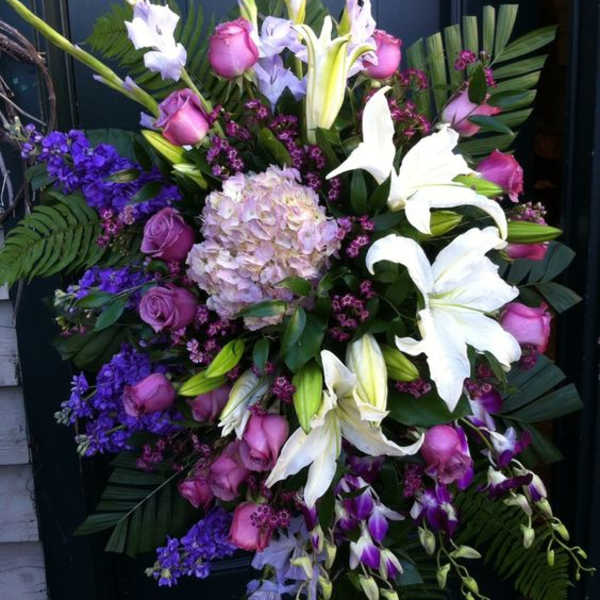 Large standing spray with white lilies, pink roses, and purple flowers