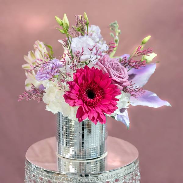 Pink and white bouquet in a mirrored vase on a reflective stand
