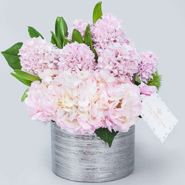 Pink hydrangeas and lilies arranged in a silver textured vase