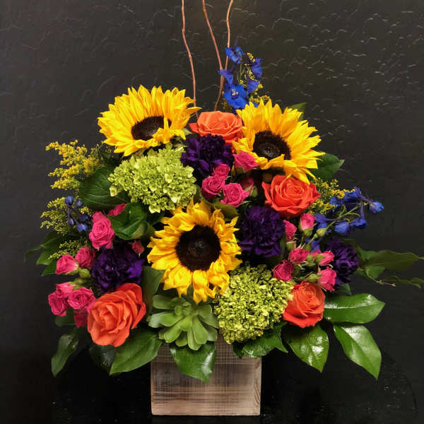 Colorful flower arrangement with sunflowers, roses, and hydrangeas in a wooden box