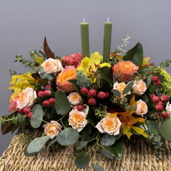 Autumn floral centerpiece with roses, yellow orchid, and two green candles