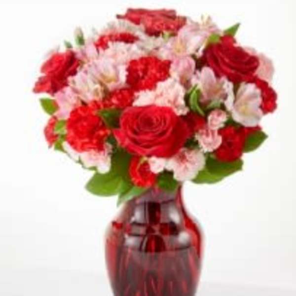 Red and pink mixed bouquet in a red glass vase