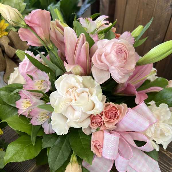 Pink and white bouquet with roses, lilies, and a ribbon bow