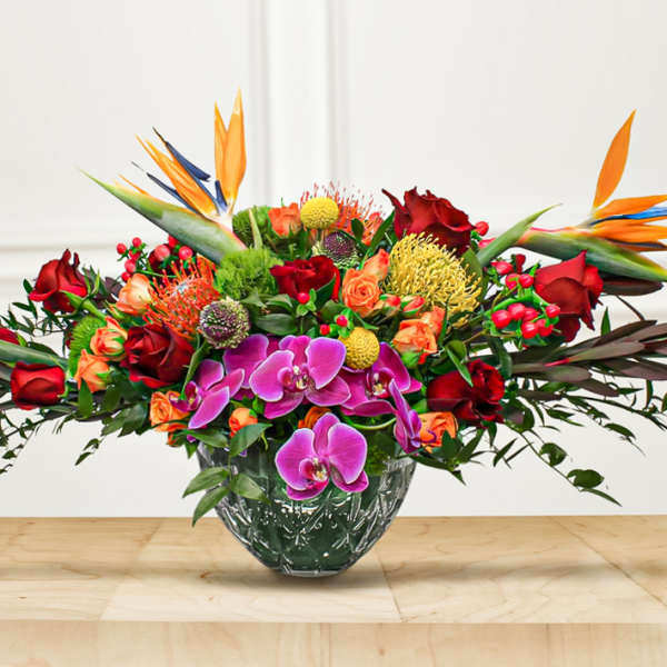 Tropical bouquet with red roses and purple orchids in a glass vase