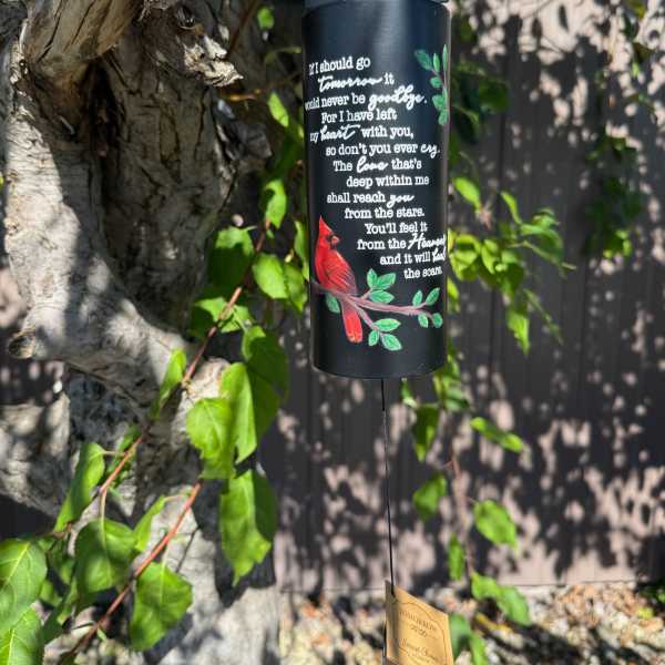 Black memorial wind chime hanging from a tree with a red cardinal design