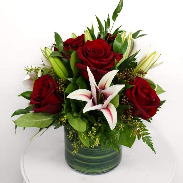 Red roses and white lilies in a green glass vase
