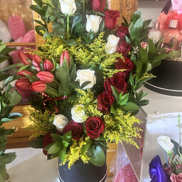 Tall bouquet of red and white roses with pink tulips in a black box