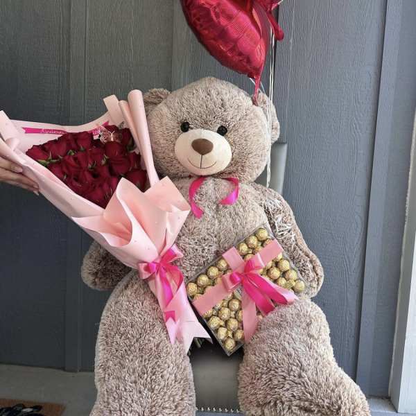 Teddy bear holding red rose bouquet, chocolates, and heart balloons