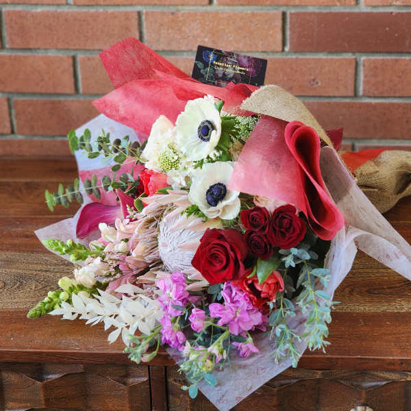 Bouquet of red and white flowers wrapped in pink paper and burlap