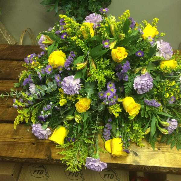Large bouquet of yellow roses and lavender flowers on a wooden table