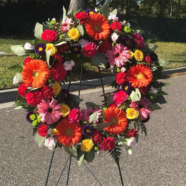 Colorful floral wreath on a black stand outdoors
