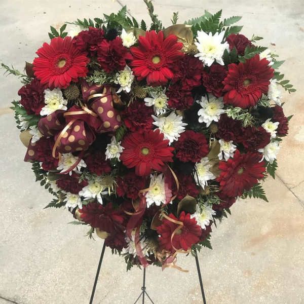 Heart-shaped floral arrangement with red and white daisies on a stand