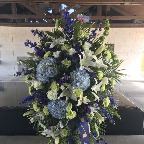 Large standing floral spray with blue, white, and green blooms