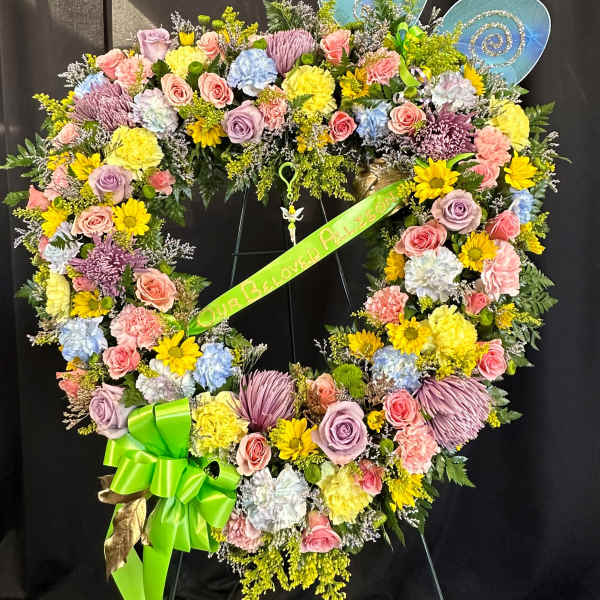 Heart-shaped floral wreath with pastel flowers and a green ribbon