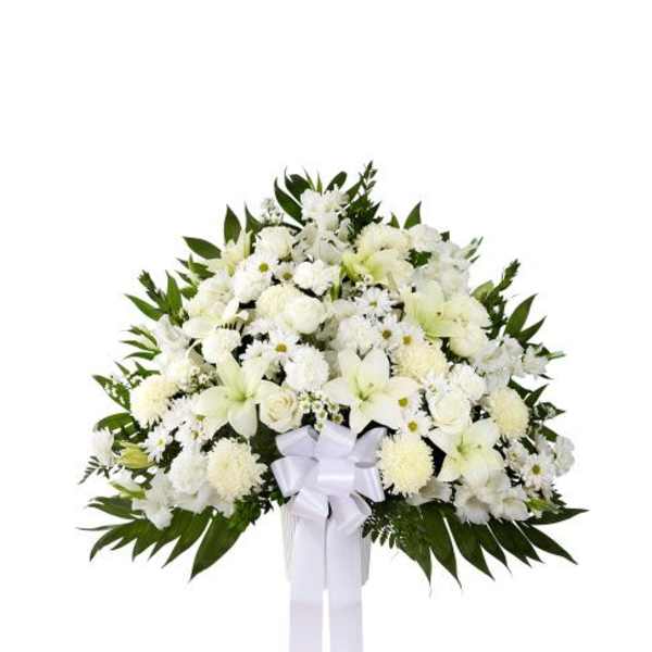 Large standing spray of white lilies, roses, and other flowers with a white bow and long ribbons