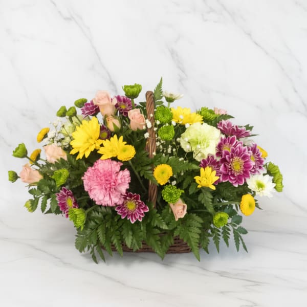 Mixed bouquet in a wicker basket with pink, yellow, white, and purple flowers