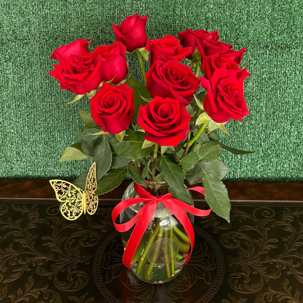 Red roses in a clear glass vase with a red ribbon