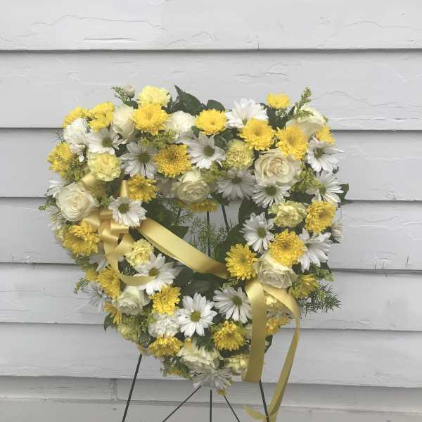 Heart-shaped wreath of white and yellow flowers with a yellow ribbon