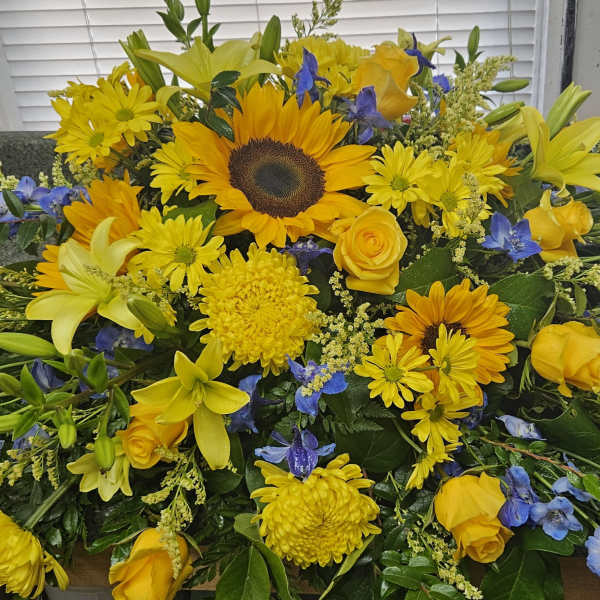 Yellow and blue mixed flower arrangement with sunflowers and roses