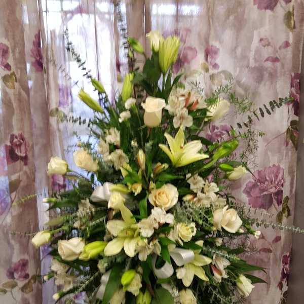 Tall white floral spray with lilies and roses on a stand