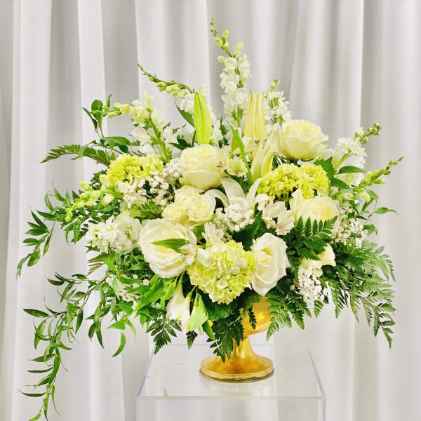 White and pale yellow floral arrangement in a gold vase
