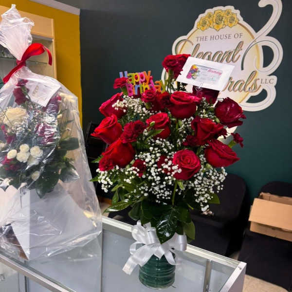 Red rose bouquet in a glass vase with baby's breath and a white ribbon