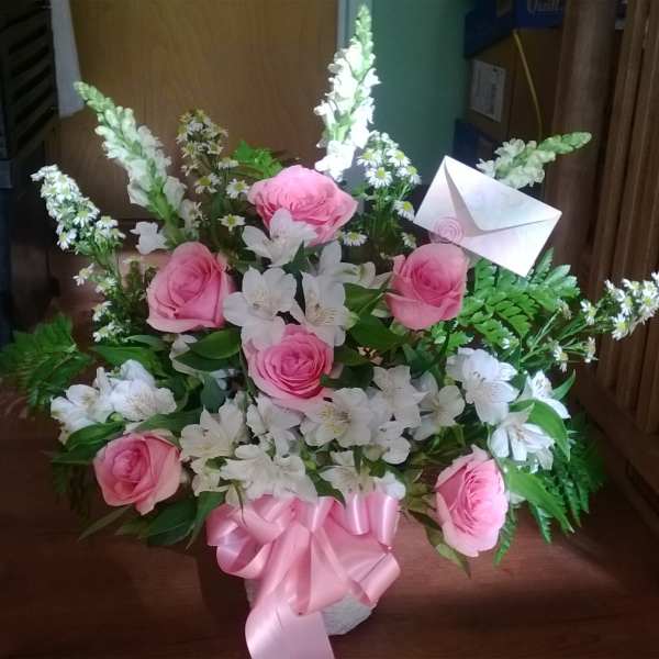 Pink roses and white flowers in a basket with a pink ribbon and envelope card
